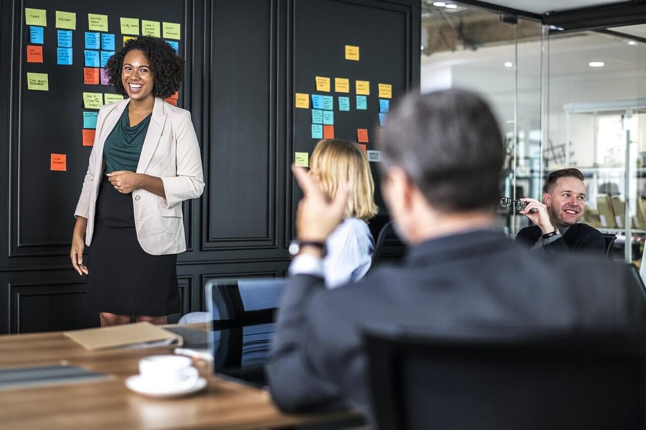 laughing woman presenting with sticky notes on wall