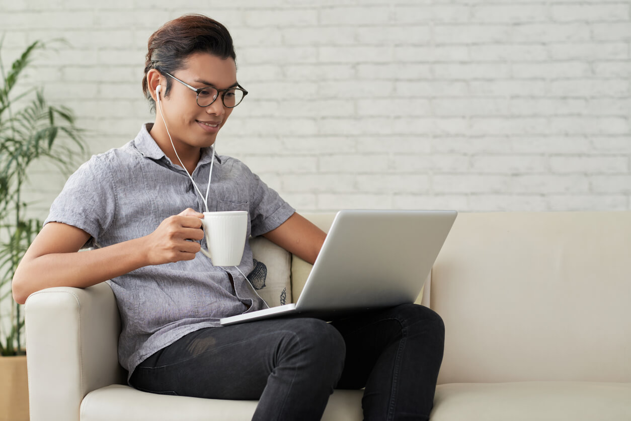 viewer with laptop on lap holding mug