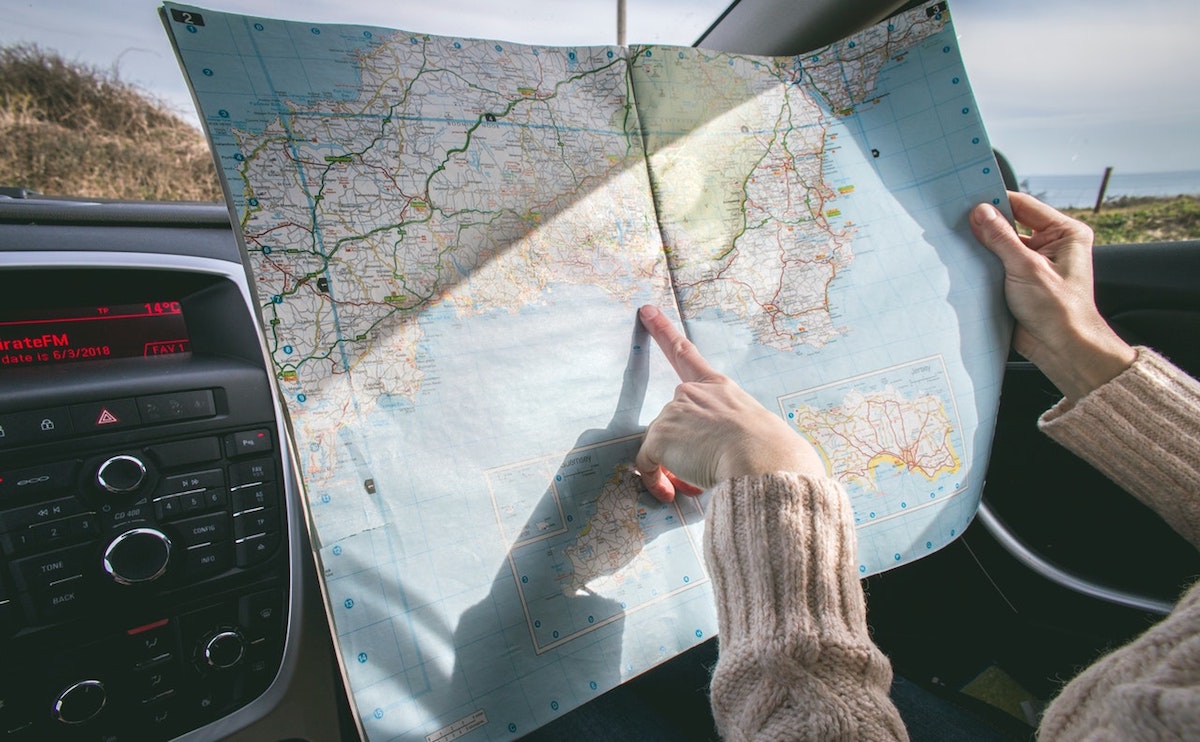 person-wearing-beige-sweater-holding-map-inside-vehicle-1252500