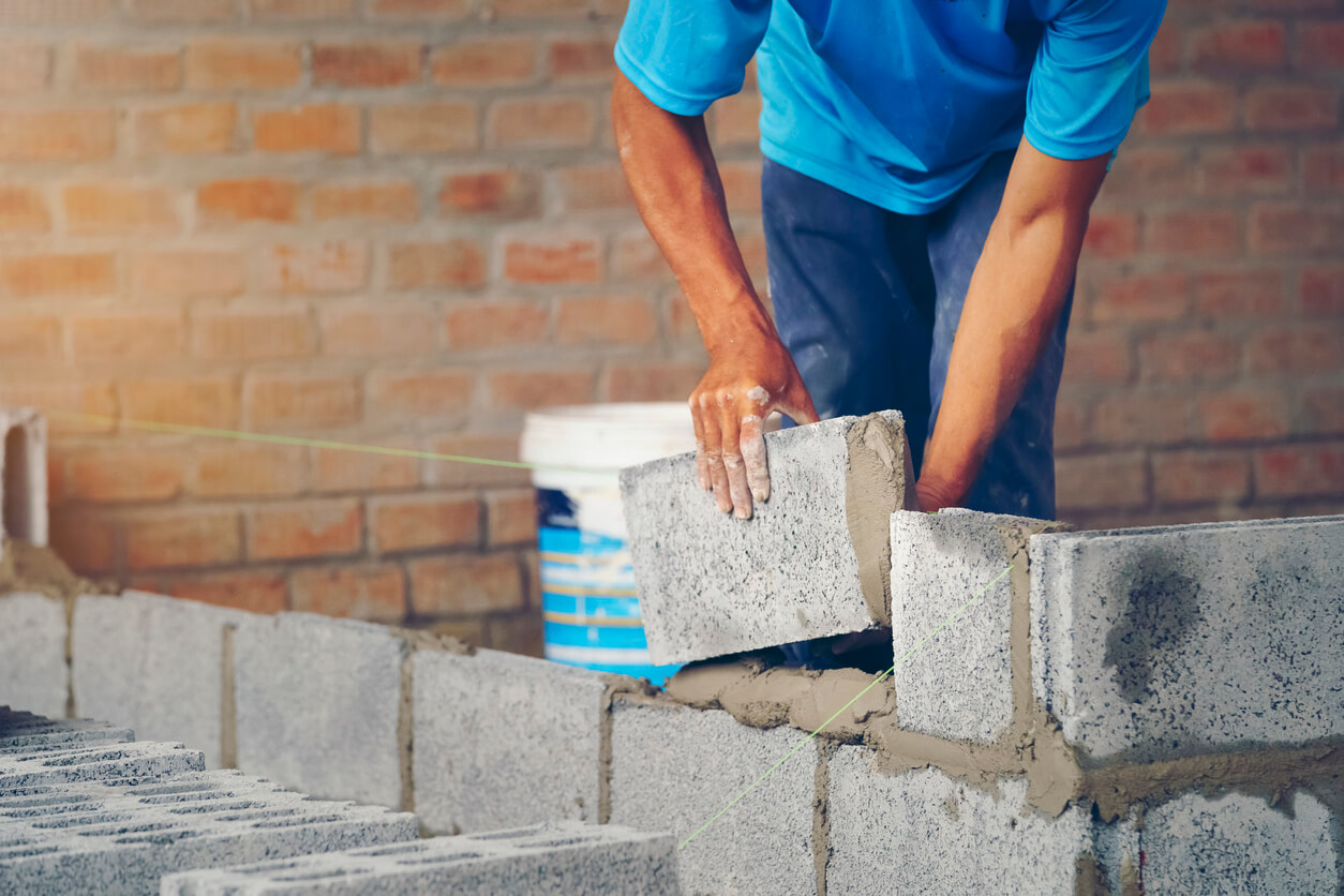 man laying down cement bricks