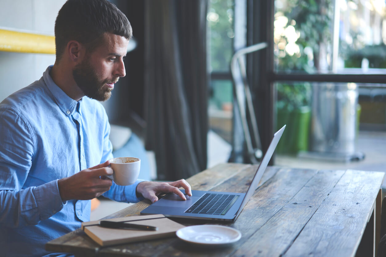 man focused on laptop holding mug