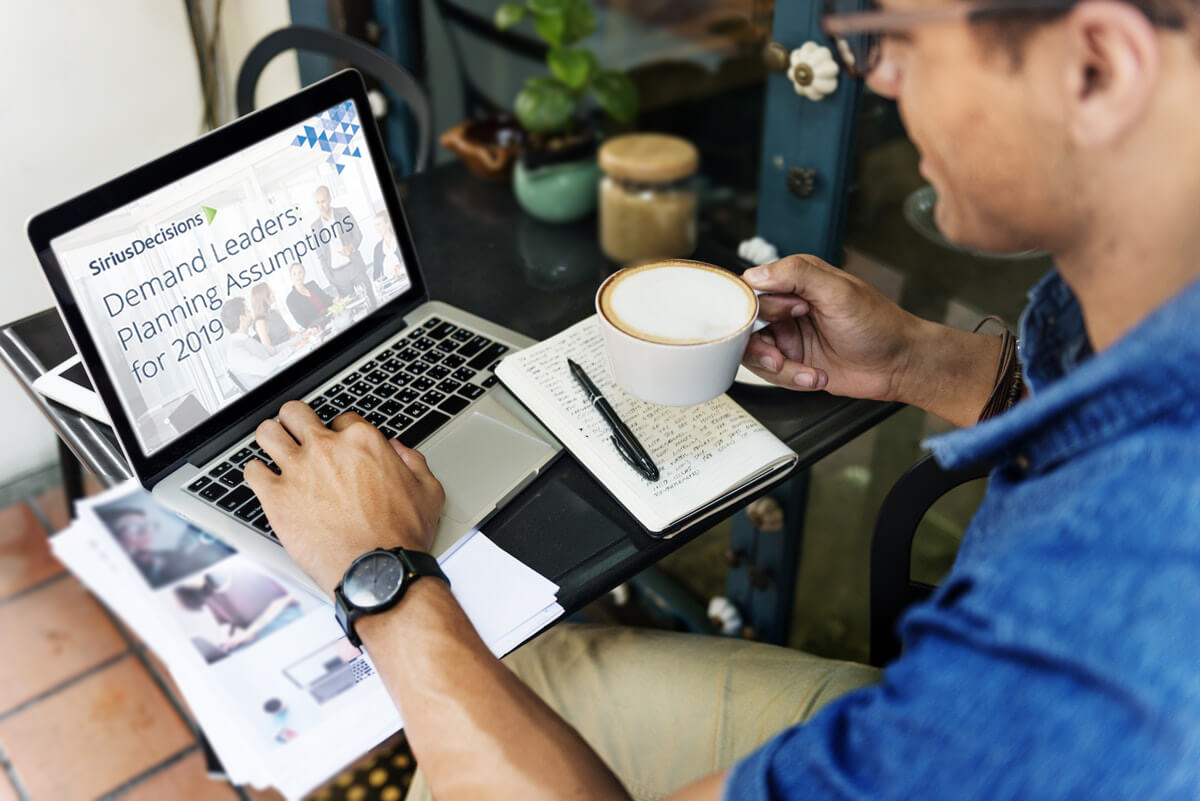 man with hand on laptop and holding coffee mug demand leaders