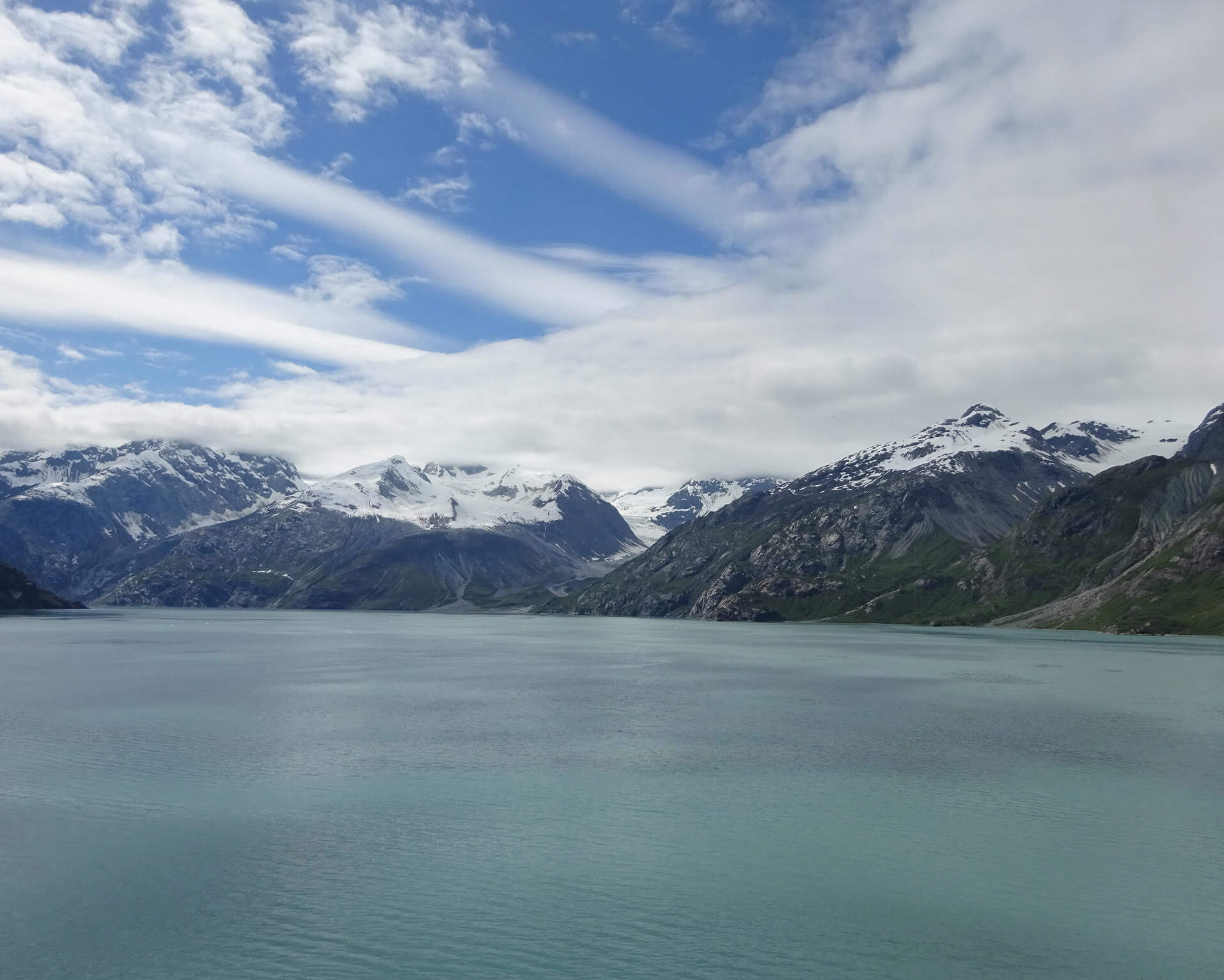 snow capped mountains above dark blue water