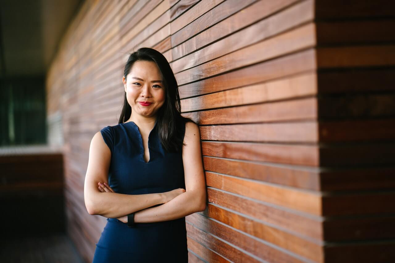 woman with arms crossed against wood wall