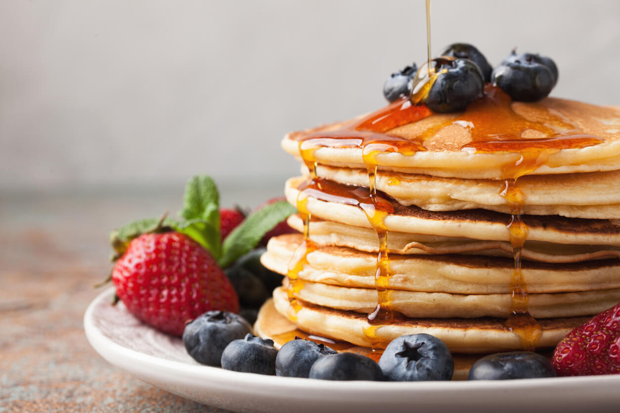 Delicious pancakes with fresh blueberries, strawberries and maple syrup